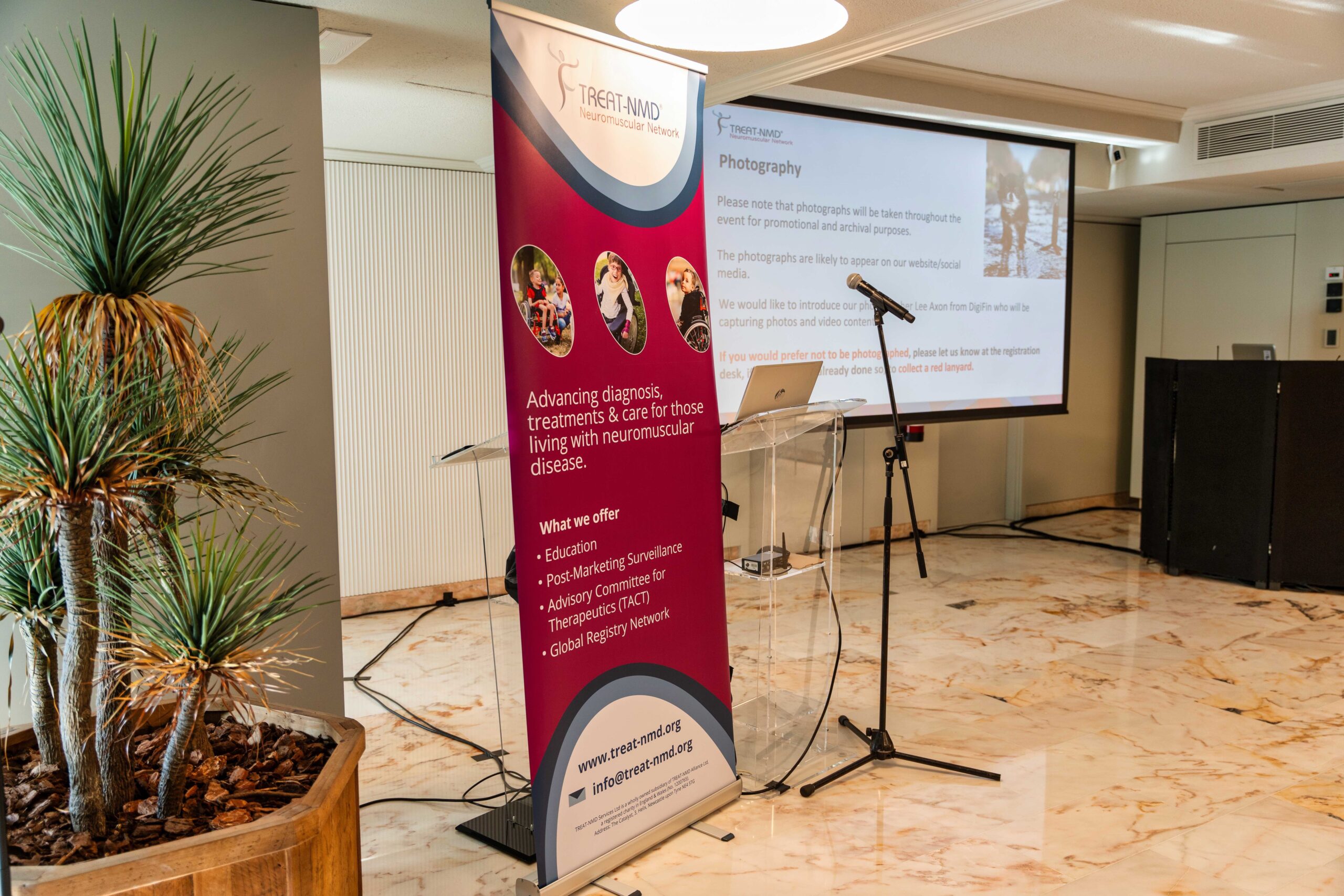 Image shows TREAT-NMD promotional banner next to microphone and screen ready for presentation.